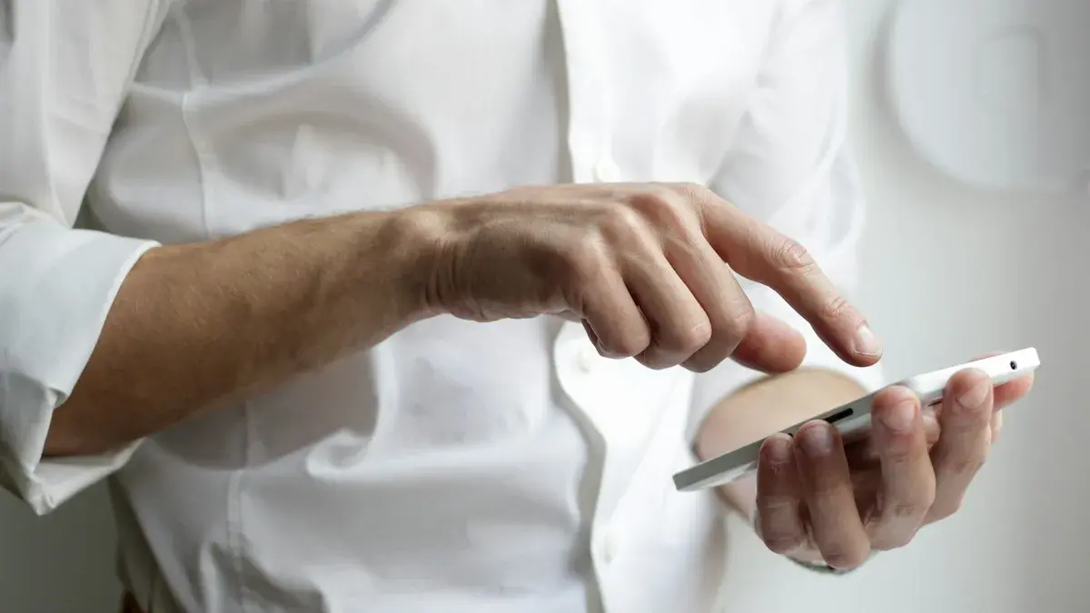 Chauffeur VTC assis au volant de sa berline consultant et souscrivant son assurance en ligne sur son smartphone